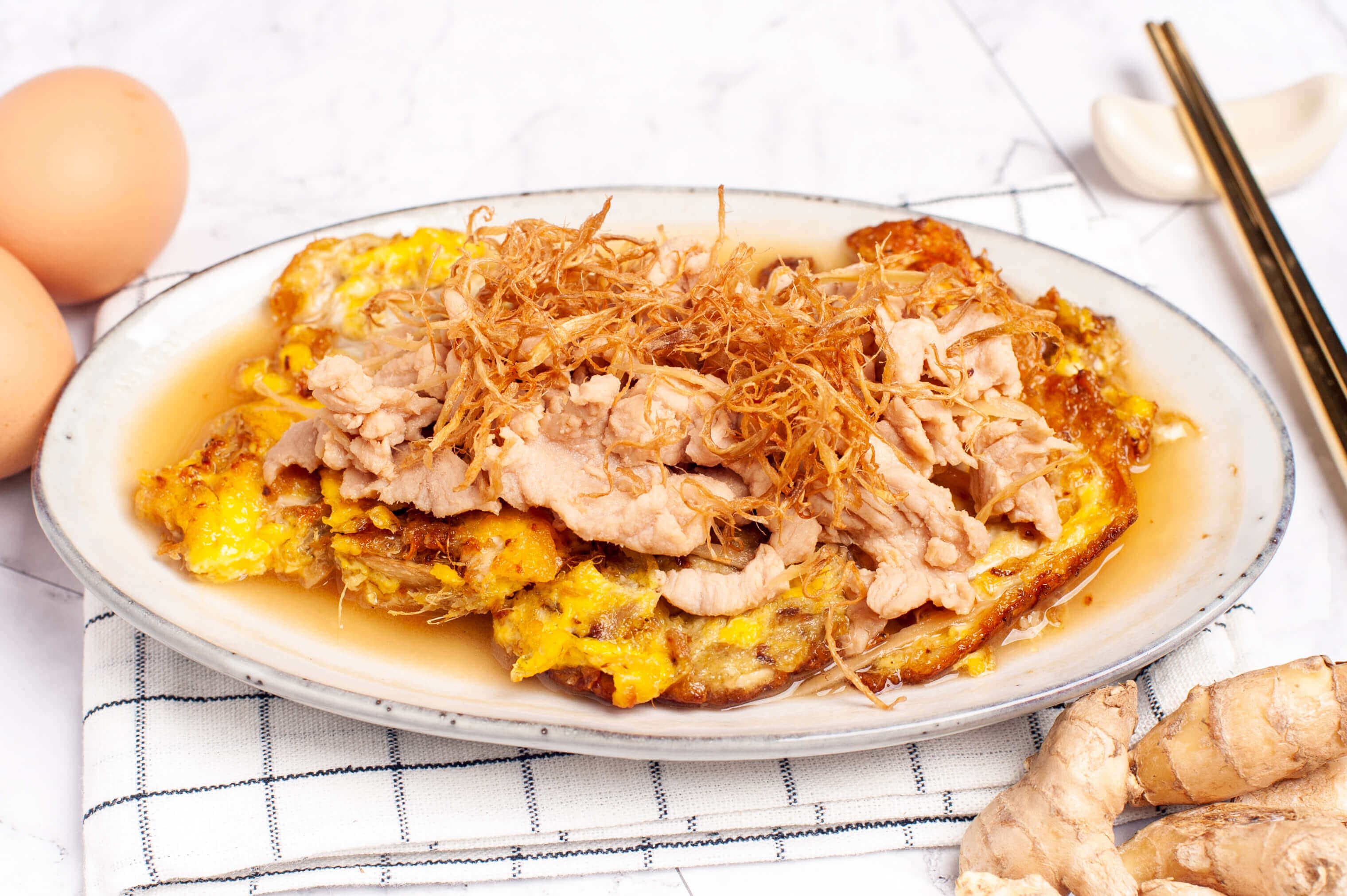 Yellow wine fried pork with ginger and egg, sliced pork over a golden fried egg in a light broth, topped with crisp fried ginger threads.